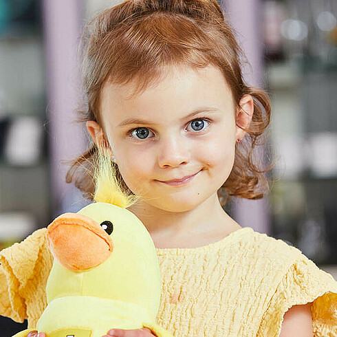Portraitbild eines Mädchens mit einer gelben Plüschente im Arm